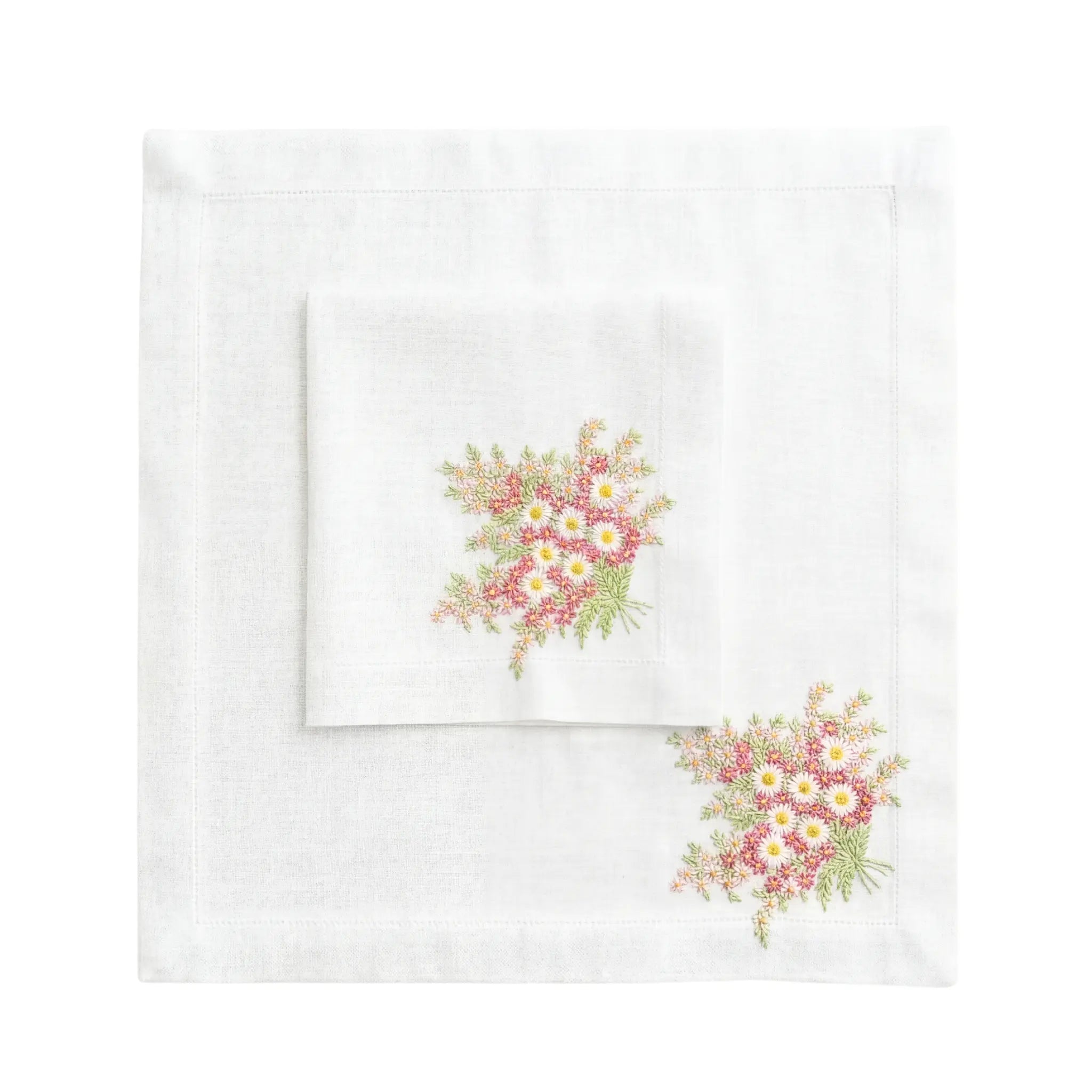 Daisy Pure Linen Dinner Napkin, Pink - Set of 2, featuring embroidered pink and yellow flowers with green foliage, displayed on a matching linen placemat.