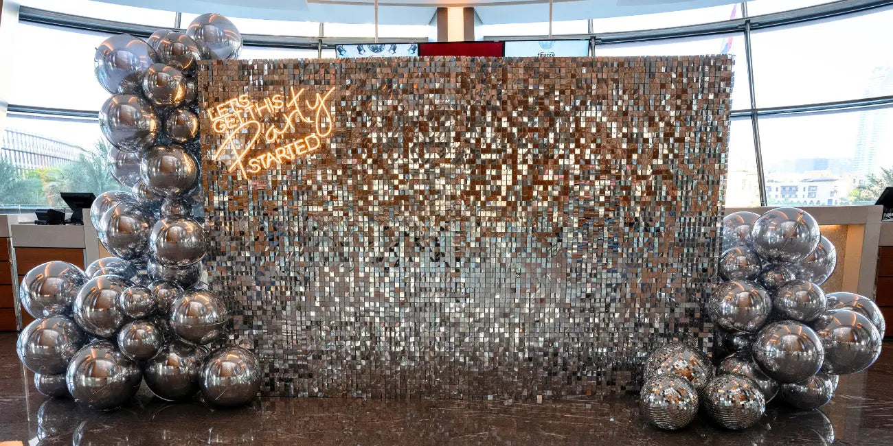 Decorative setup with silver balloons and a sparkling backdrop in an indoor setting.