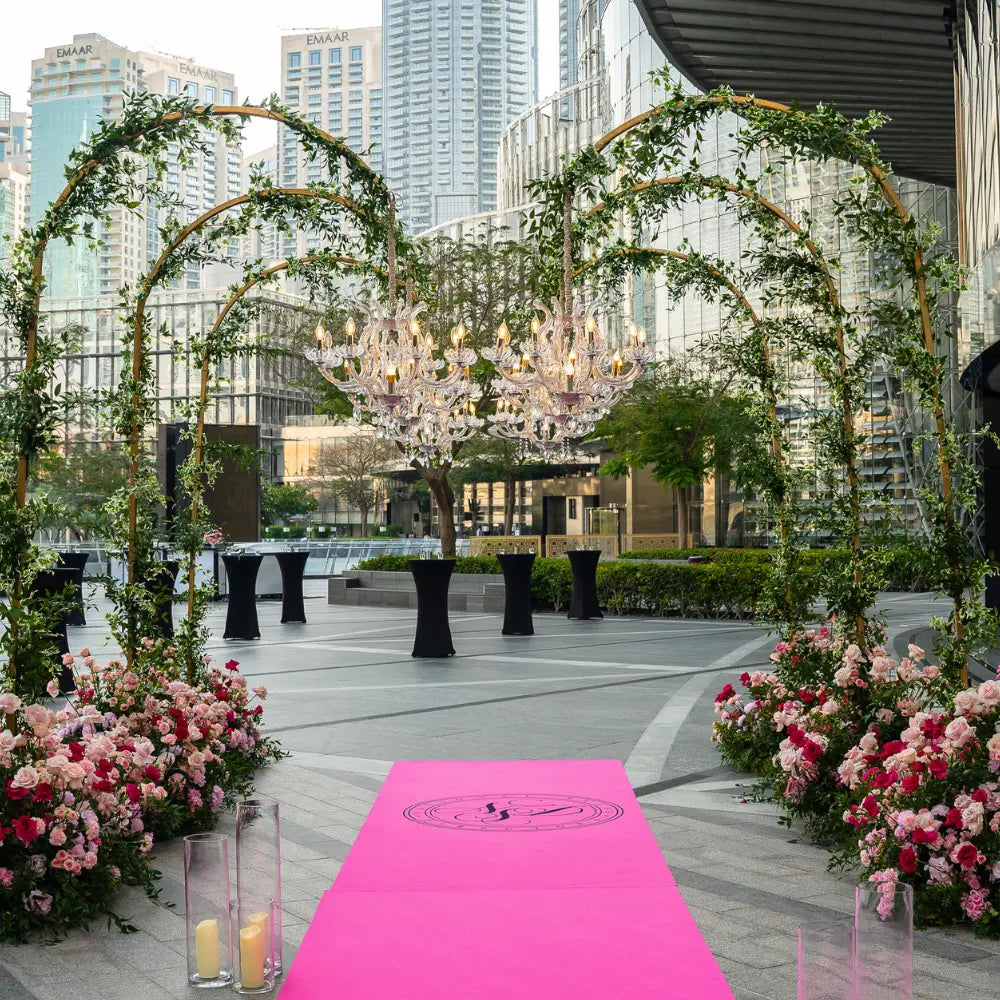 Decorative archway with floral arrangements and a chandelier in an urban setting.