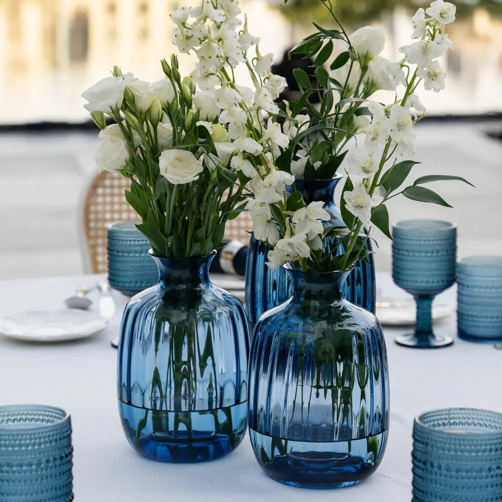 Blue vases with white flowers on a table setting outdoors