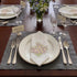 White tablecloth with three folded napkins, each featuring embroidered pink and white daisies with greenery, highlighting the Pink Daisy Pure Linen Dinner Napkin - Set of 4.