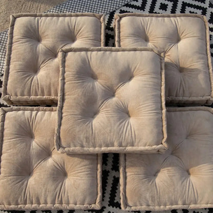 FLOOR CUSHION VELVET: Five tufted, beige velvet floor cushions with piped edges, set on a black-and-white textile. Ideal for event seating or decor.