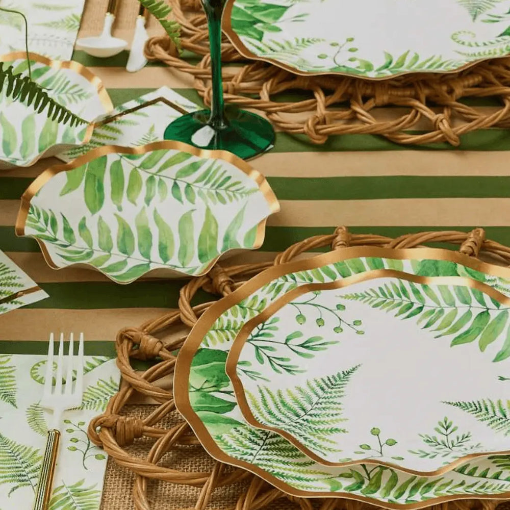 Table setting with green leaf-patterned plates on a striped tablecloth.