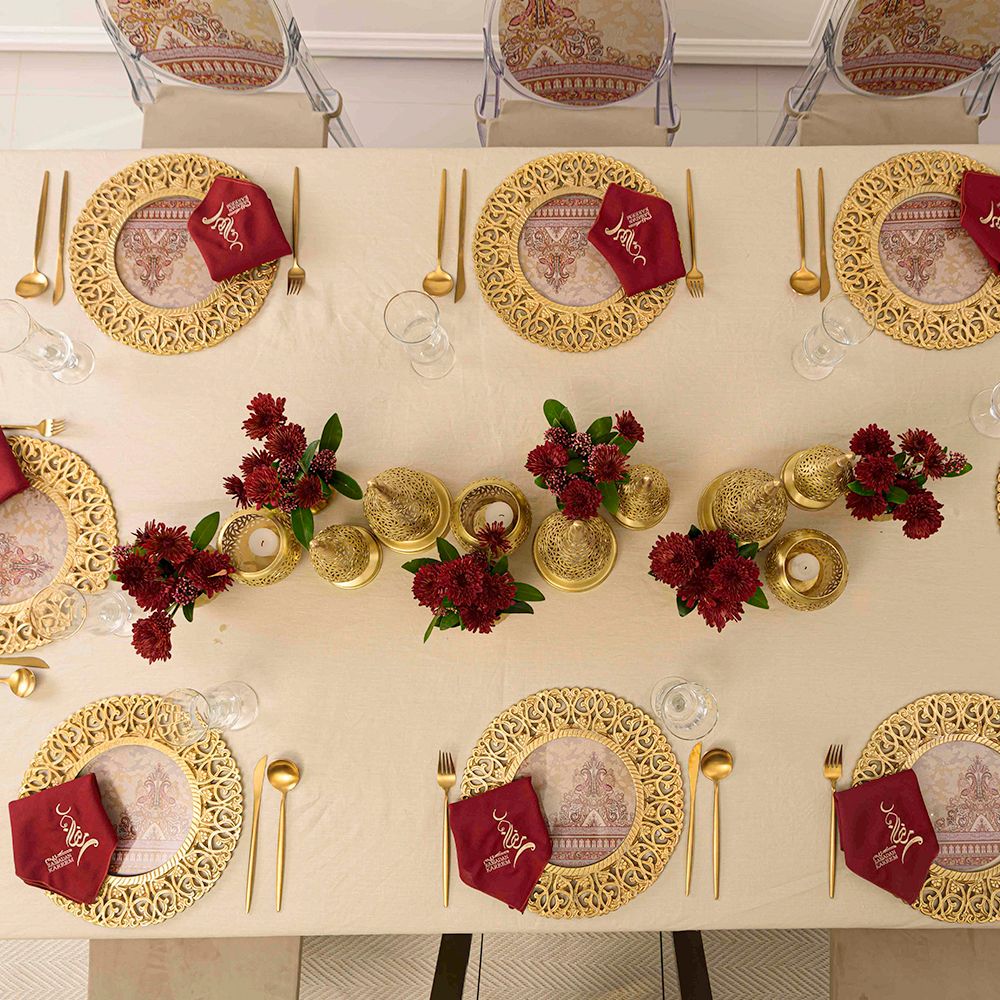 Vintage Arabesque Collection: A table set with gold plates, red napkins, and floral centerpiece, ideal for Ramadan dining, available for rental from Party Social.