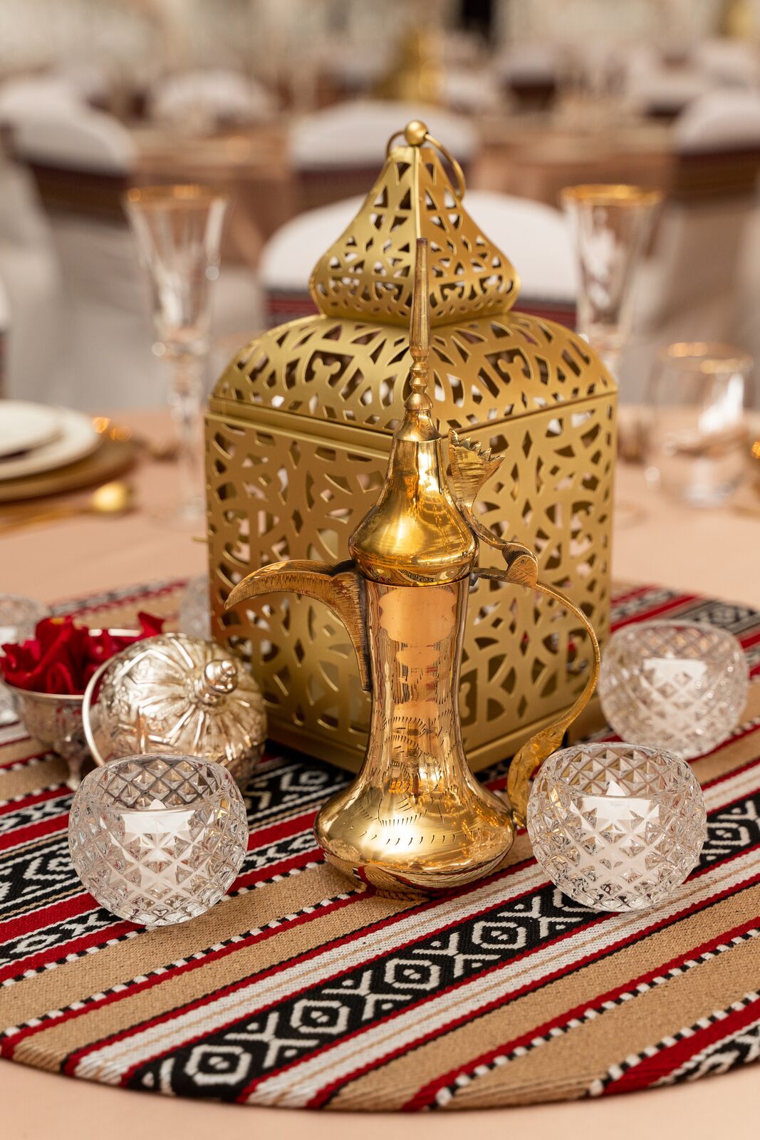 Gold Arabic Lantern on a table, showcasing elegant design. Ideal for event decor, available in sizes from 28cm to 50cm. Candles not included.