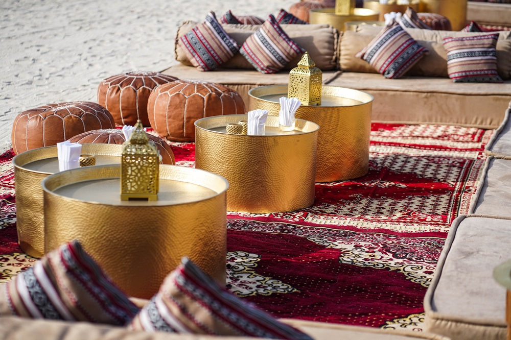 ALUMINIUM COFFEE TABLE with Moroccan-inspired design, displayed with pillows and other decor on a rug. Available in three sizes for versatile event styling.