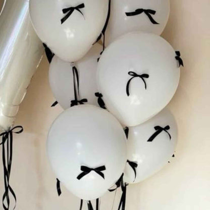 Signature Letter Balloon Bouquet featuring white helium balloons with black ribbon bows, including customizable alphabetical balloons for an elegant, dreamy graduation decoration by Party Social.