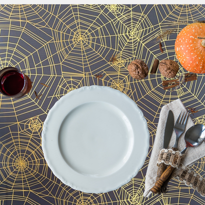 Spider Web Polyester Halloween Tablecloth on table with pumpkin and wine glass, featuring silverware on a napkin, perfect for themed events.