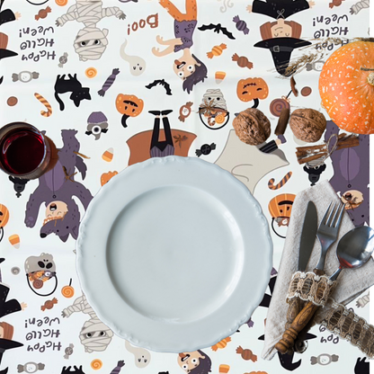 Trick or Treat Polyester Halloween Tablecloth on a table set with a white plate, cutlery, a pumpkin, and a glass of red liquid.