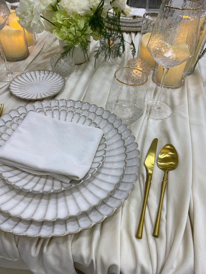 Classic Cream-Dining Setup featuring elegant white and gold tableware with scalloped edges, gold flatware, and floral centerpiece, perfect for formal gatherings or special occasions.