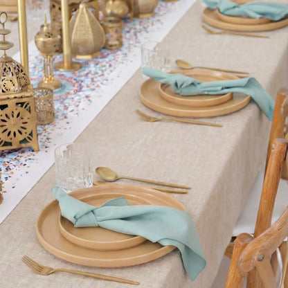 Golden Hour Iftar- Dining Setup features a boho-chic table with wooden chargers, teal napkins, gold flatware, glass tumblers, gold lanterns, and candleholders for eight guests.