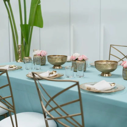Elegant dining table with RECTANGULAR TABLECLOTH COTTON LINEN, gold charger plates, brass decor, and white seat cushioned chairs, set for a sophisticated gathering.