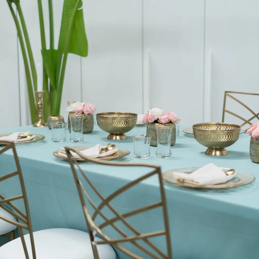 Elegant dining table with RECTANGULAR TABLECLOTH COTTON LINEN, gold charger plates, brass decor, and white seat cushioned chairs, set for a sophisticated gathering.