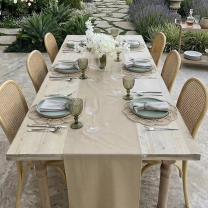 Linen Blend Table Runner elegantly drapes an outdoor dining table, complemented by rattan chairs and coordinated tableware, ideal for special occasions.