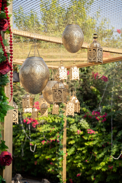 Vintage Hanging Pendant lanterns displayed in a garden setting, showcasing intricate metal patterns. Ideal for enhancing event decor. Candles not included.