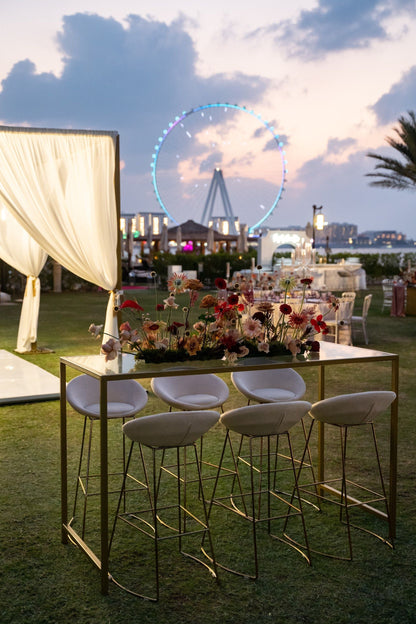 High Glass Rectangular Table with Gold Base, set outdoors near a ferris wheel, ideal for corporate events, complements Party Social&