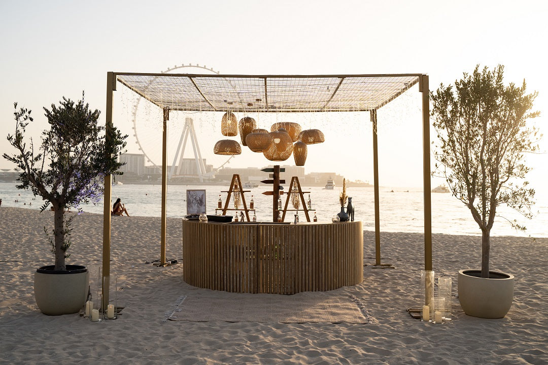 SEMI WOODEN BAR UNIT set up on a beach, surrounded by trees and a wooden fence, ideal for garden or home events.