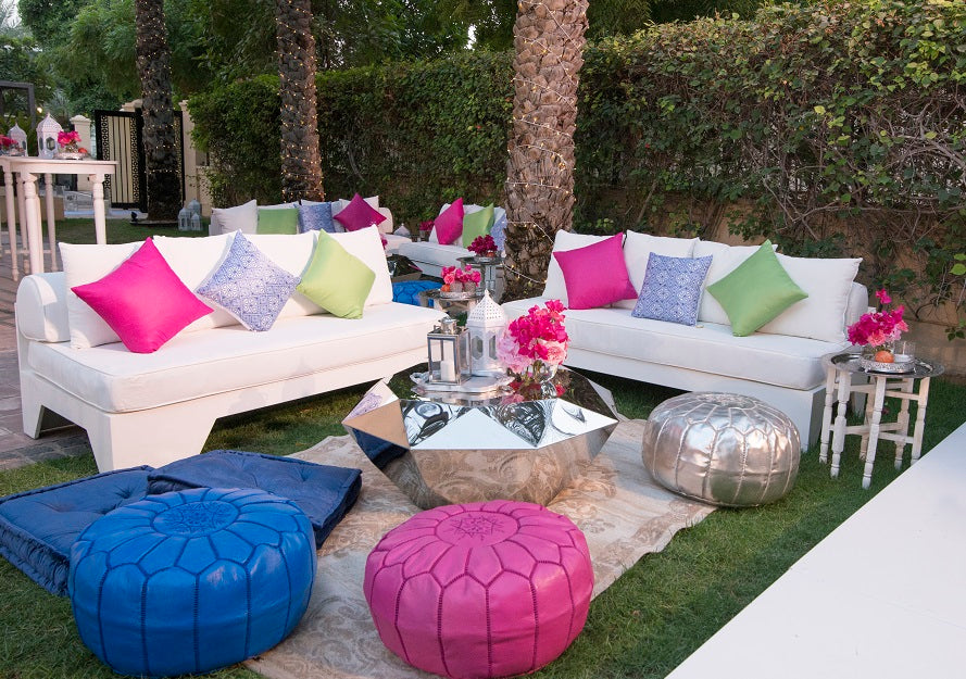 Mirrored silver coffee table featured outdoors among white couches and colorful pillows, ideal for elegant party settings by Party Social.