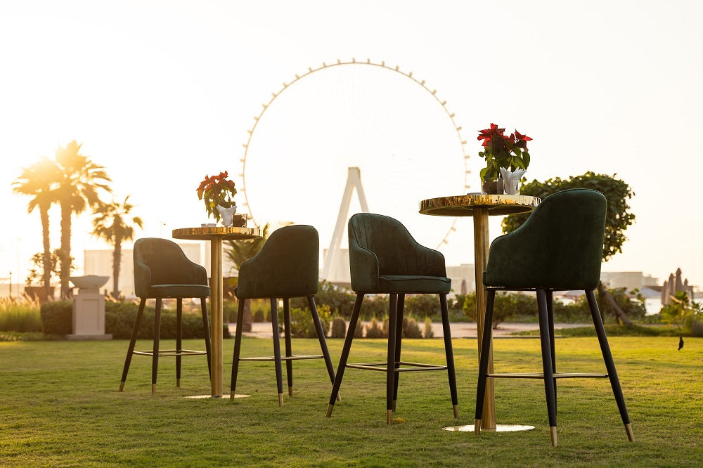 Gold cocktail tables on grass with a Ferris wheel in the background, ideal for versatile event setups.