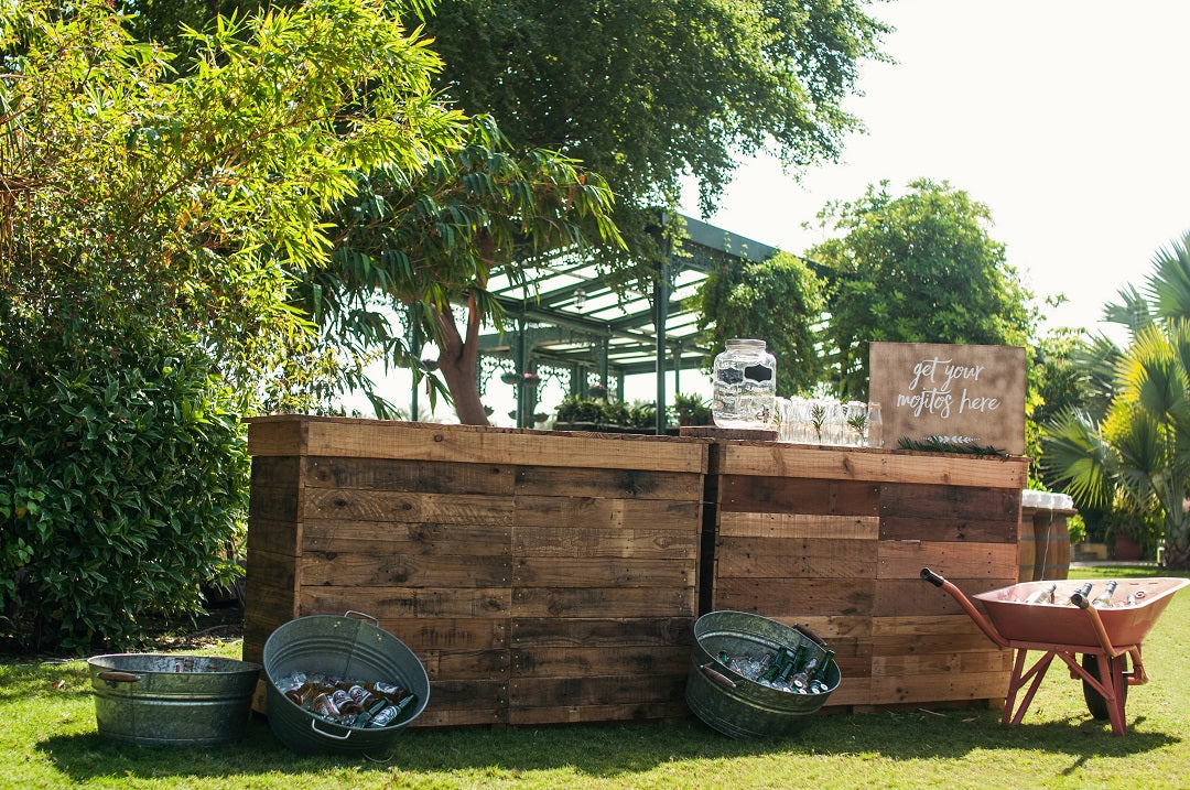 Rustic Bar Unit displayed outdoors with buckets of beer, ideal for events. Complements rustic tables and benches, features an interior shelf for storage.