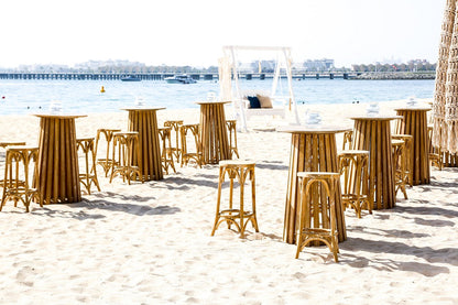 WOODEN COCKTAIL TABLE on a beach, part of a versatile collection suitable for garden or home settings, featured among outdoor furniture.