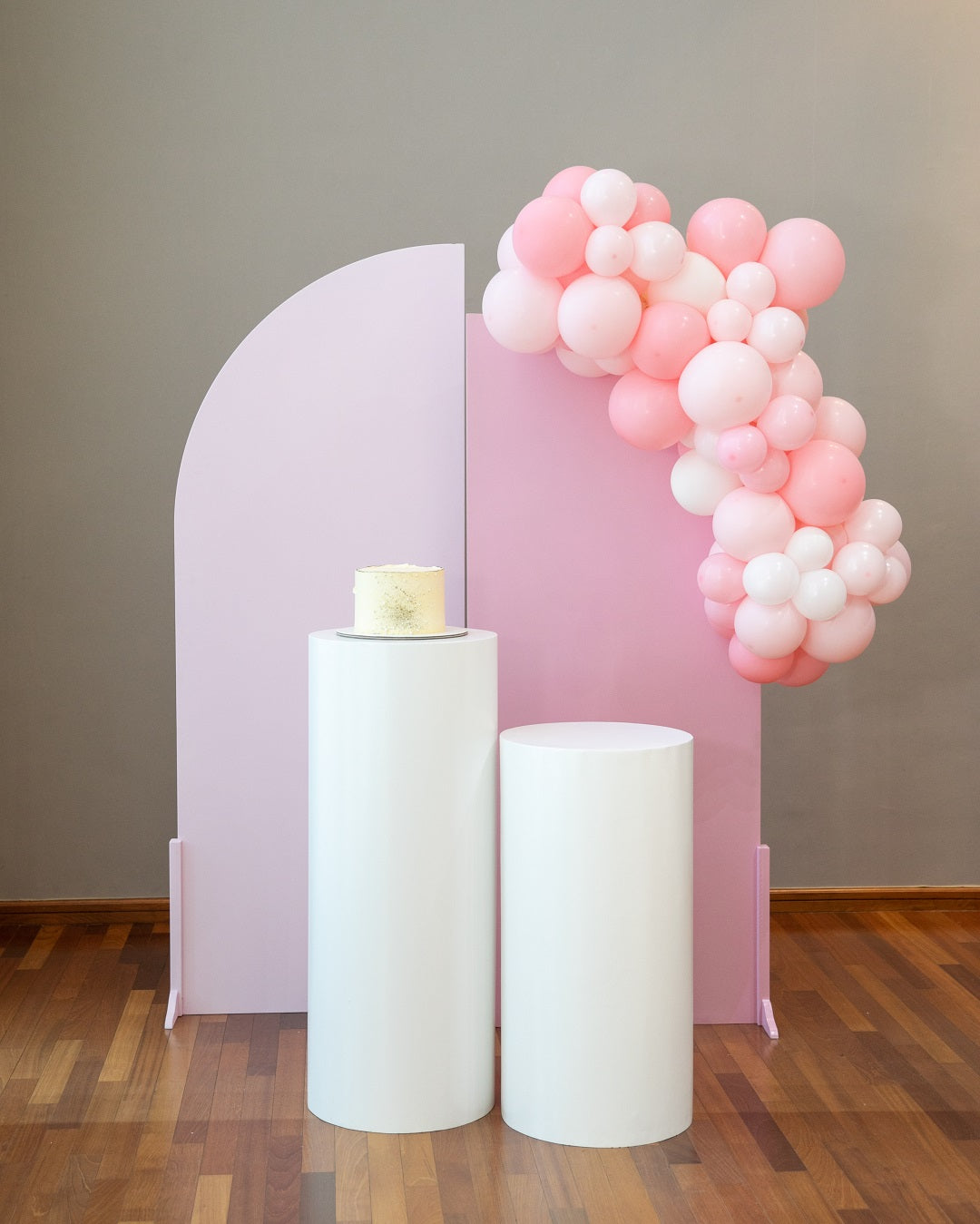 WHITE WOOD CURVED BACKDROP on a wooden floor, adorned with pink and white balloons, ideal for enhancing event decor at weddings or parties.