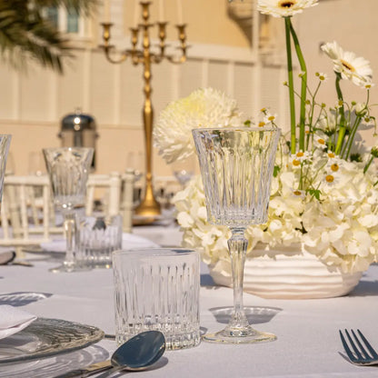 Crystal Paris Glassware Collection: Elegant cut-glass tumbler and goblet, perfect for upscale events, set on a refined table with hydrangeas and candelabra.