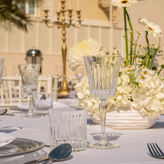 Crystal Paris Glassware Collection: Elegant cut-glass tumbler and goblet, perfect for upscale events, set on a refined table with hydrangeas and candelabra.