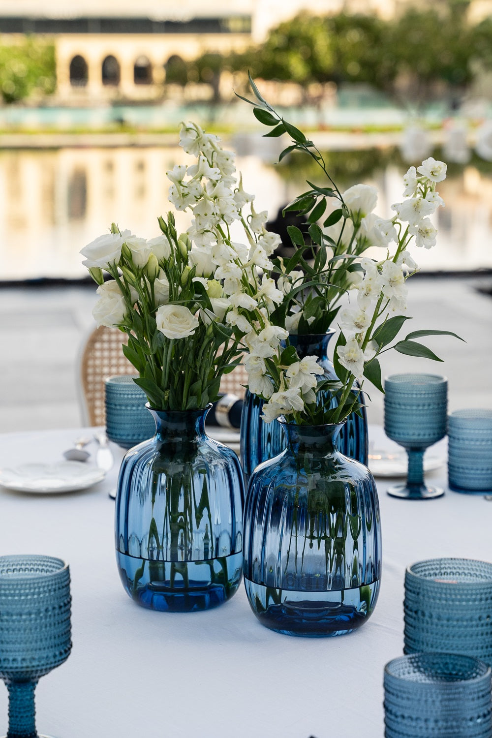 Blue COLORED GLASS VASE arranged with white flowers, ideal as an elegant home or event centerpiece, enhancing any table setting with its timeless design.