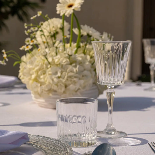 Crystal Paris Glassware Collection: Close-up of cut crystal tumbler and goblet on a white tablecloth, perfect for elevating upscale events with elegant, light-catching design.