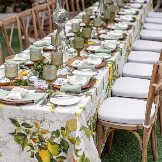 Limoncello Citrus Pure Linen Tablecloth adorns an outdoor banquet table, set with lemon motifs, elegant place settings, and lush greenery for a garden-themed event.