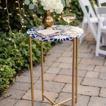 Metal Legs w/ Tabletop Cocktail Table with gold base and blue mosaic top, adorned with napkins, drink, and vase, on a patio setting.
