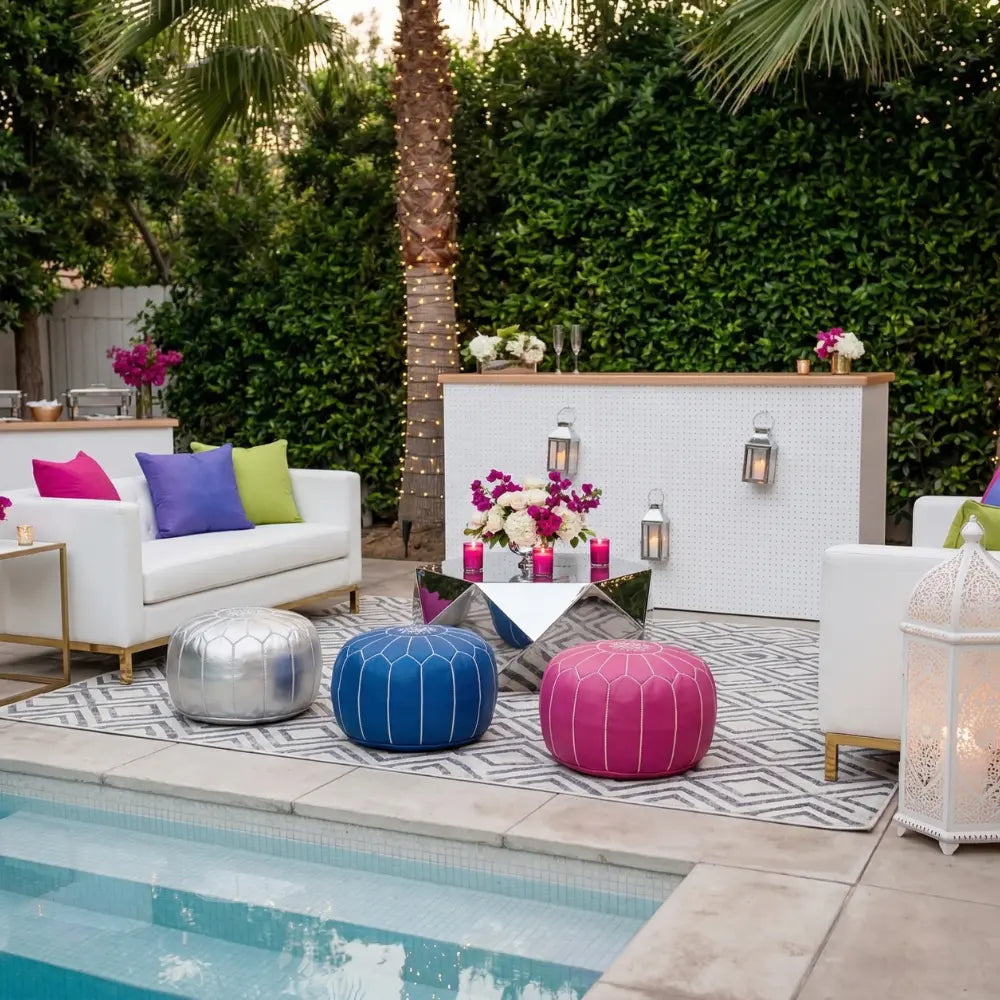 Modern Bar Unit beside pool, adorned with lanterns and flowers, complements vibrant poufs, sofas, and a geometric rug, creating a stylish, party-ready ambiance.