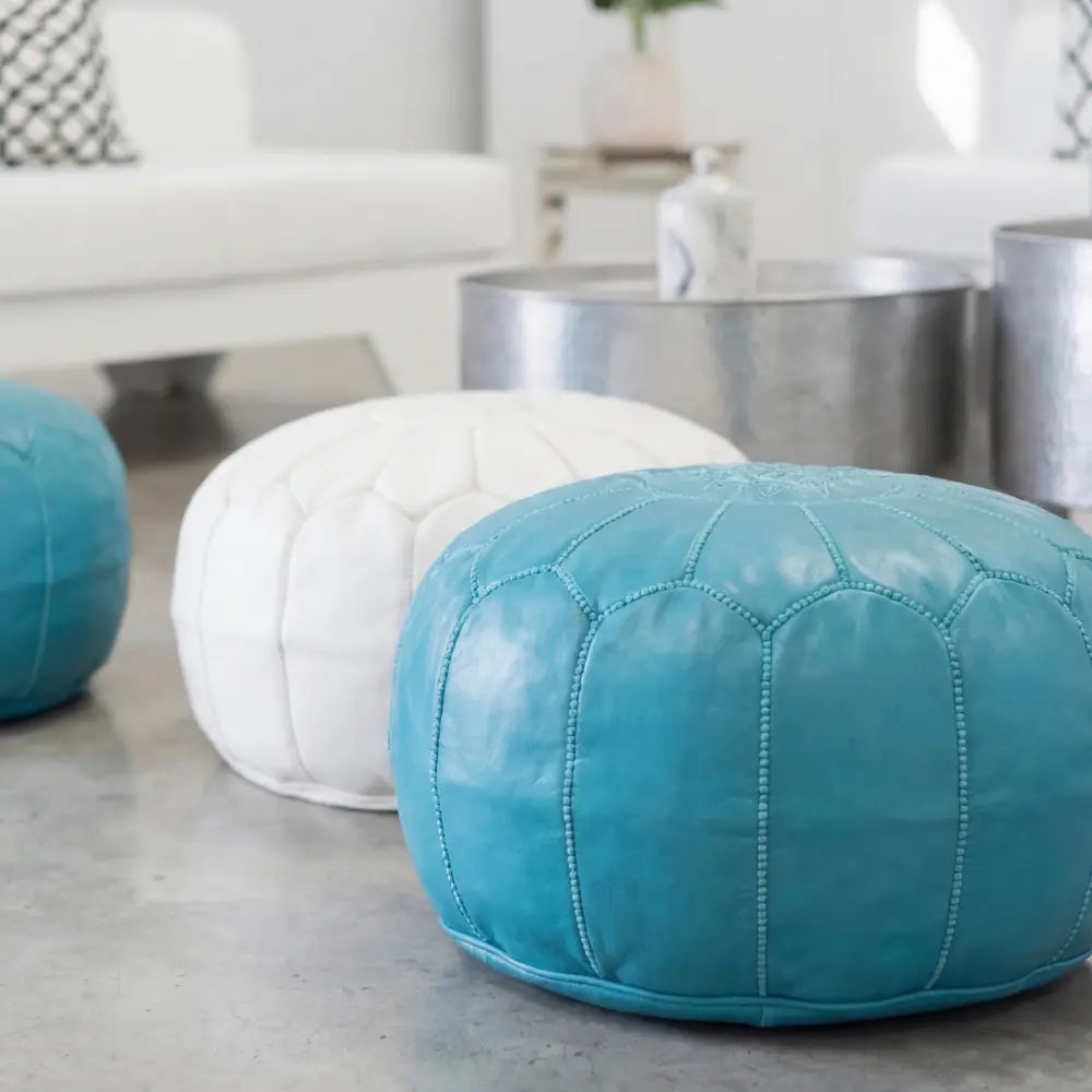 Moroccan Leather Poufs on a polished floor, showcasing bright turquoise and white designs, ideal for gatherings, reflecting Party Social&