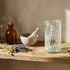 Decorative glass with engraved design on a wooden surface with books and bottles.