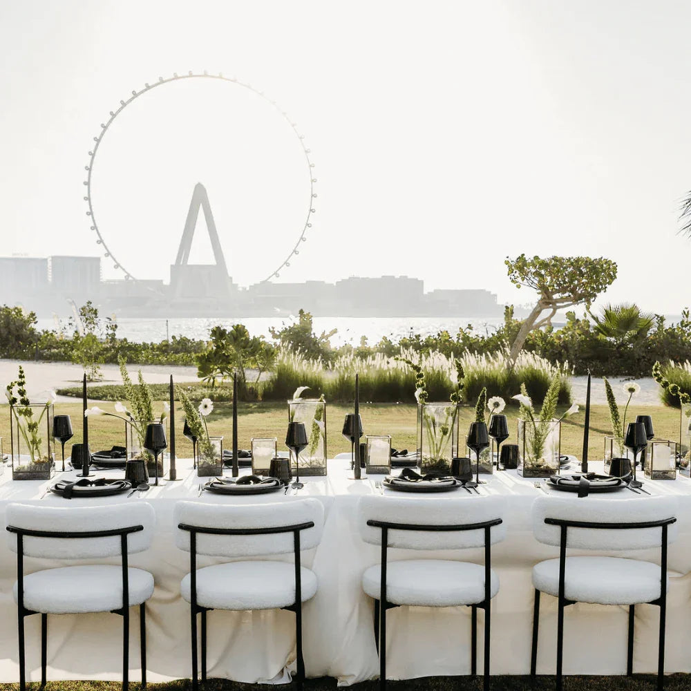 Dining table set with white modern chairs in a outdoor hotel setting with a Dubai Eye in the background.