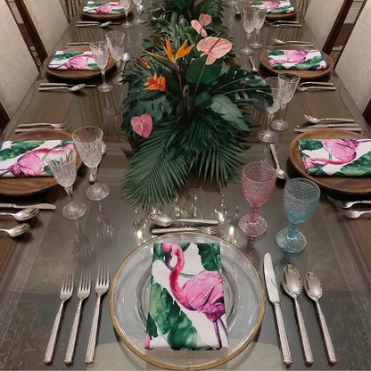 NAPKIN - FLAMINGO SATIN elegantly adorns the formal dining table, featuring vibrant flamingos and tropical leaves, complemented by crystal glasses and gold-rimmed chargers.