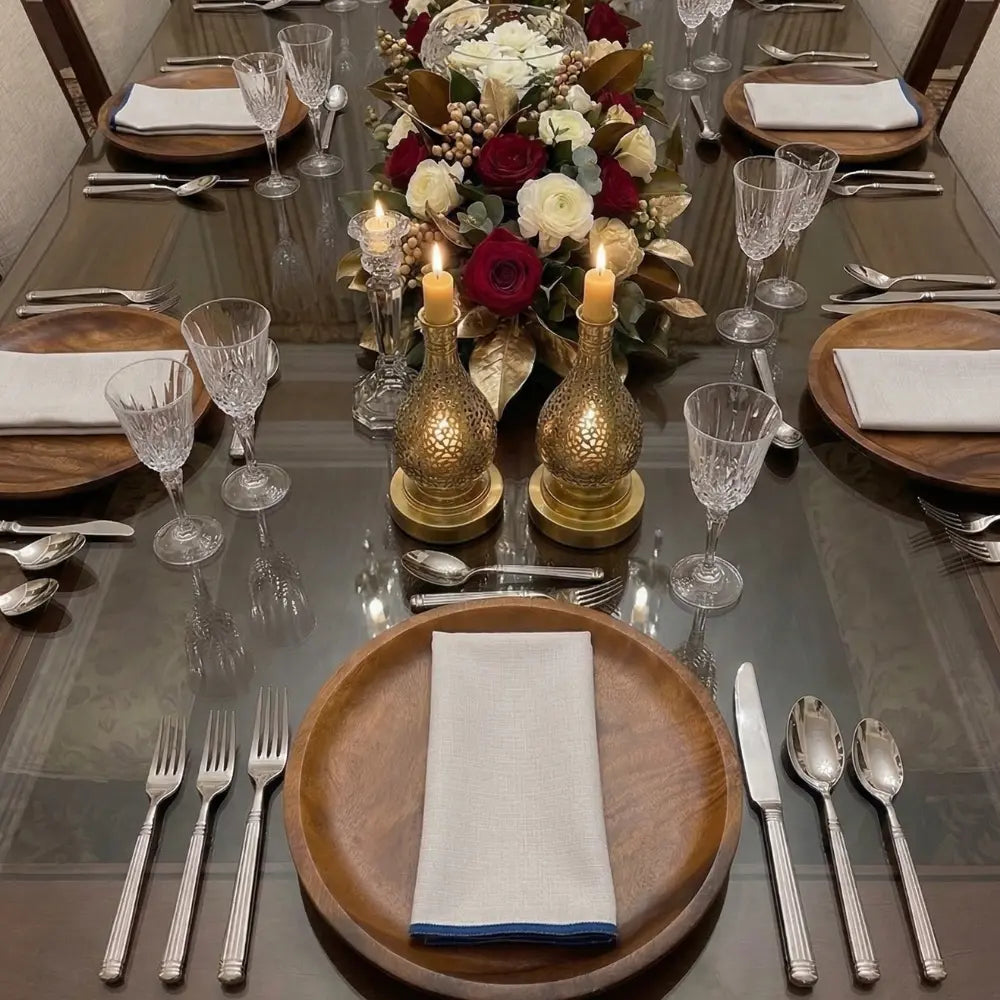 NAPKIN WHITE W/ LINE elegantly folded on a wooden charger plate, part of a refined dining setup with crystal glasses, floral centerpiece, and lit candleholders.
