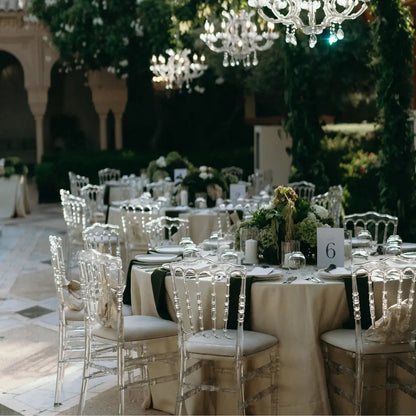 Elegant outdoor setup featuring NAPOLEON ACRYLIC CHAIR, blending timeless design with modern transparency, surrounding tables set for a formal event with glassware and floral centerpieces.