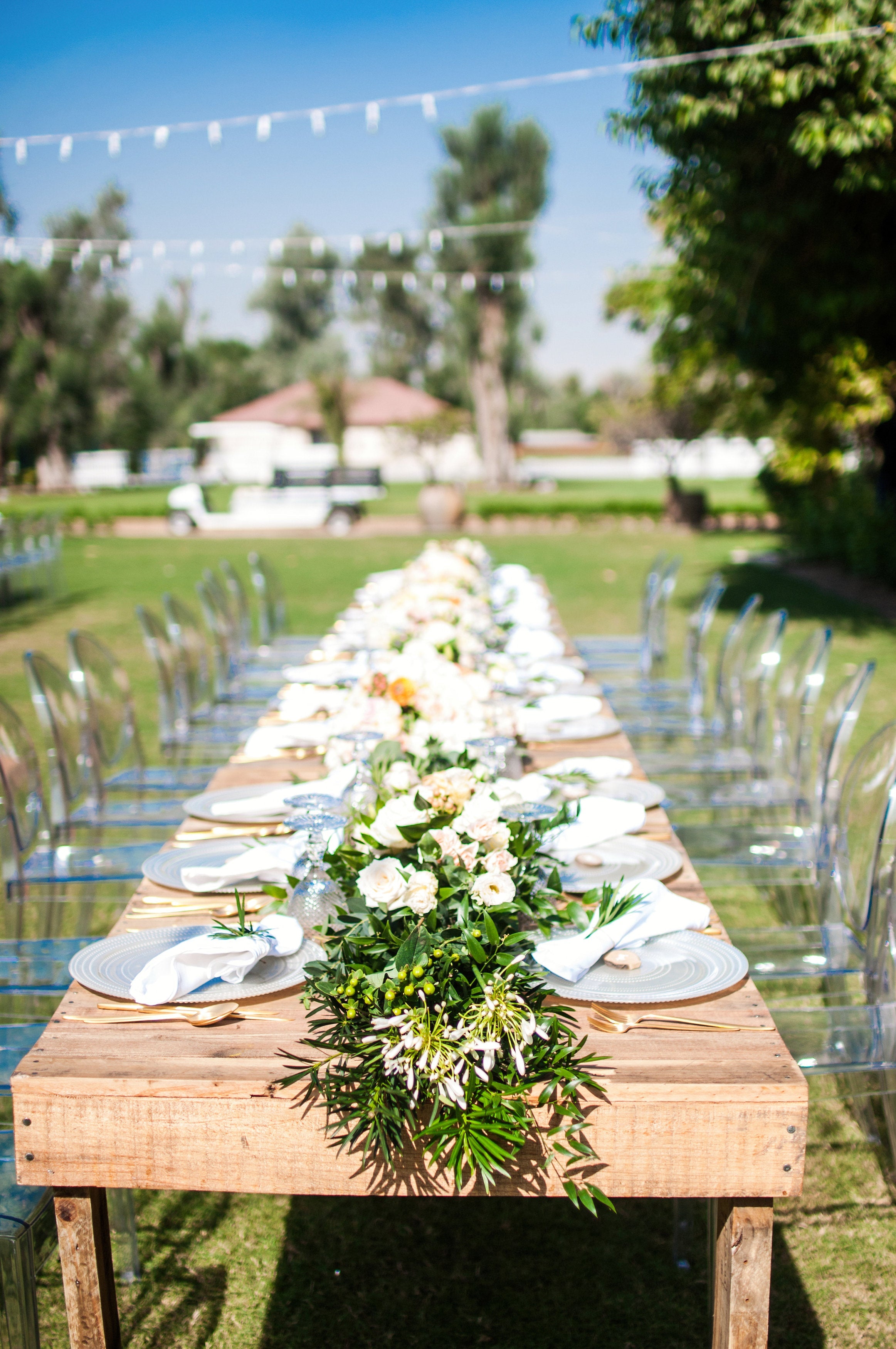 Recycled wooden dining table set outdoors, adorned with white plates and flowers, ideal for events hosted by Party Social.