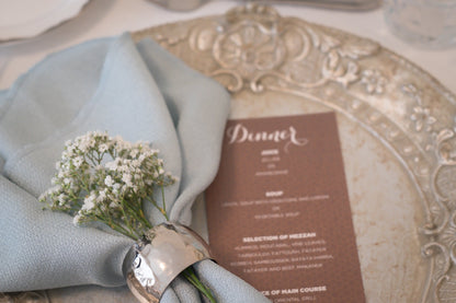 Hammered dome napkin ring on a floral napkin, ideal for elegant tablescapes. Available in gold or silver, perfect for enhancing event decor.