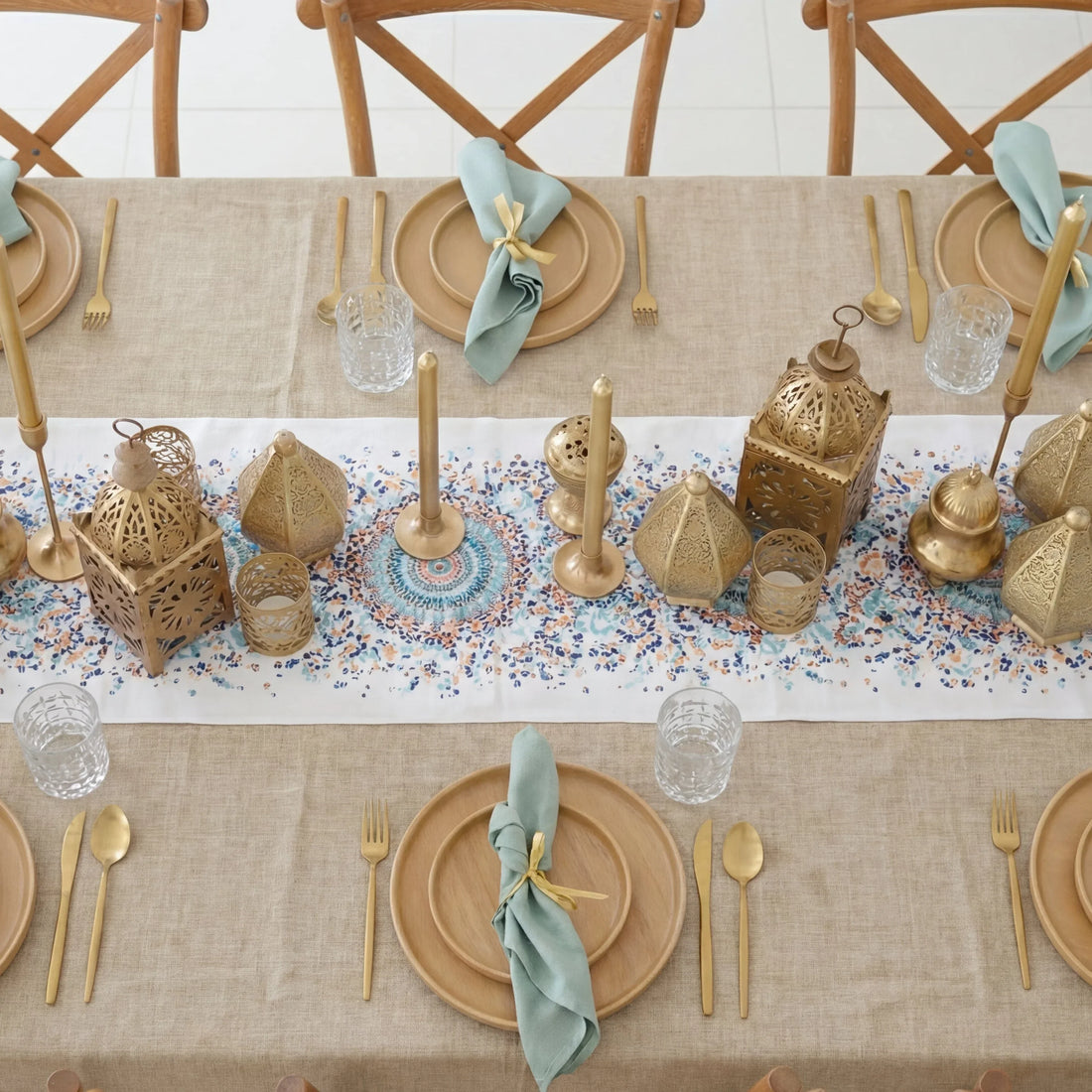 Golden Hour Iftar-Dining Setup features a sophisticated tablescape for eight, showcasing wooden charger plates, gold-tone flatware, faceted glasses, and decorative brass lanterns.