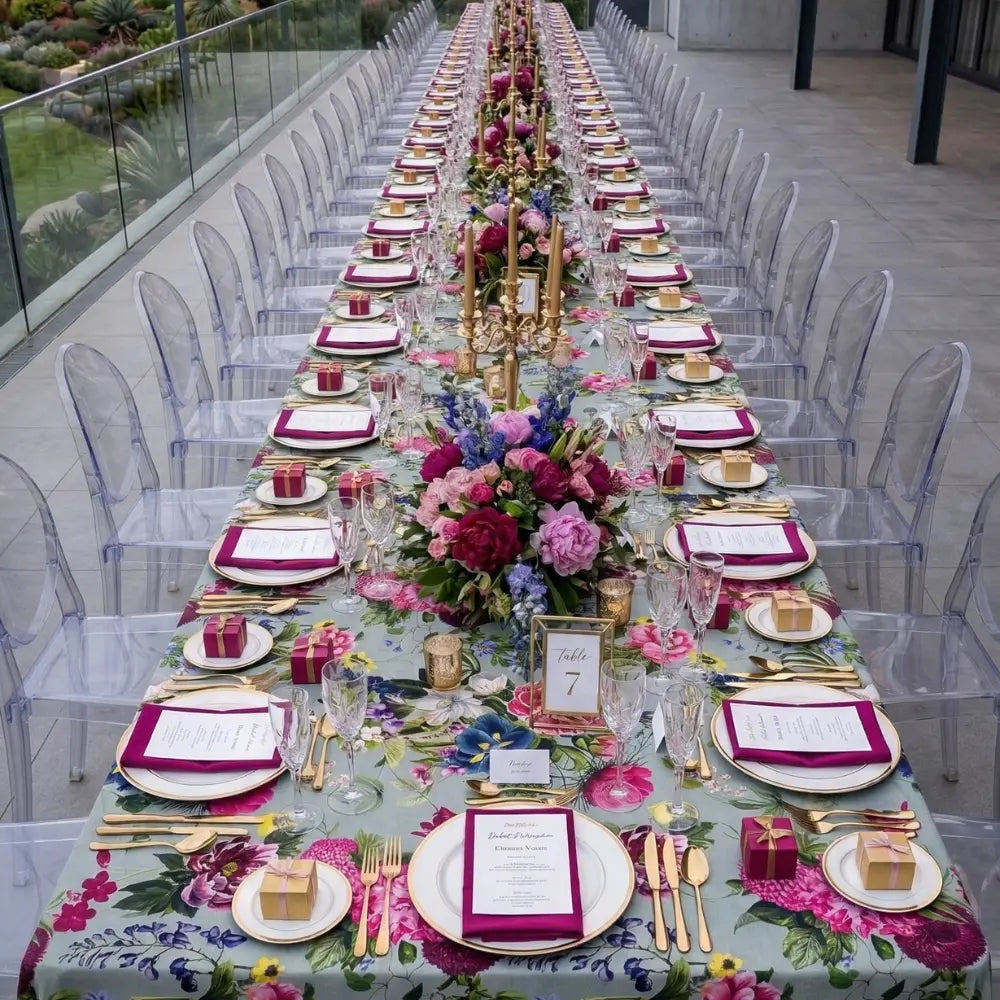 Pink Peonies Rectangular Tablecloth elegantly covers a long banquet table with floral motifs, adorned with coordinated place settings featuring gold accents and lush floral arrangements.