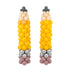 Two balloon sculptures shaped like corn cobs, made from yellow, peach, beige, gray, and dusty pink balloons, set against a plain white background.