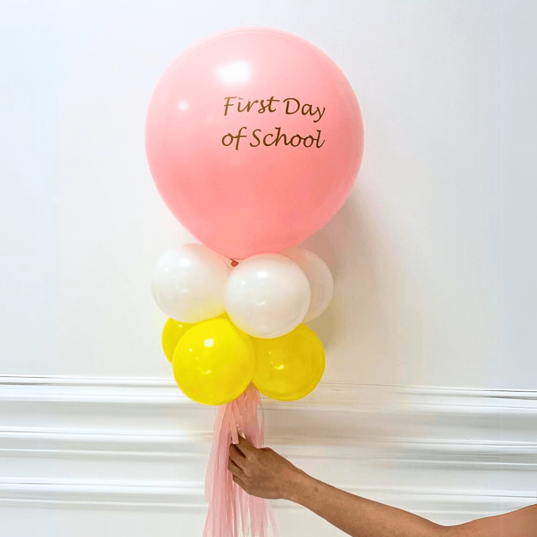 Personalised Back to School Balloon Wand featuring a vibrant 12-inch balloon, custom message, and matching tassel, held by a hand, ideal for memorable photos.