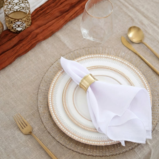 Modern Gold Cutlery Collection enhances an elegant place setting with gold-detailed plates, a gold napkin ring, and matching flatware on a linen tablecloth.