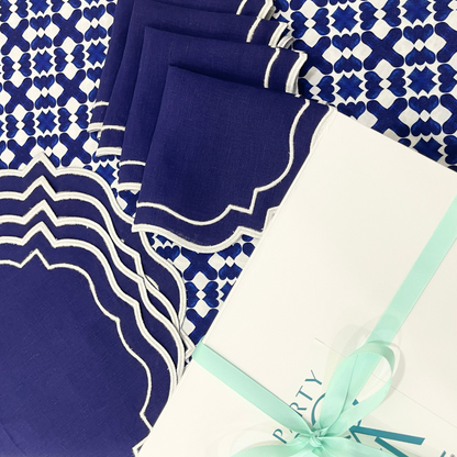 The Iftar Table Edit Gift Box featuring navy napkins, a patterned tablecloth, and a white gift box with aqua ribbon, perfect for Ramadan celebrations.