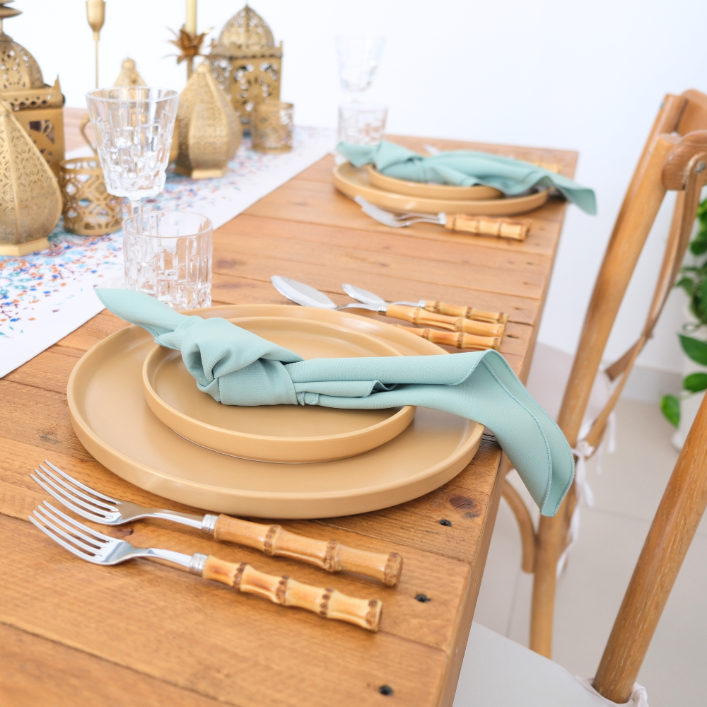 Mustard Ceramic Matte Plates set on a wooden dining table, paired with sea-foam napkins and bamboo-style cutlery, accented by brass lanterns for a party setting.