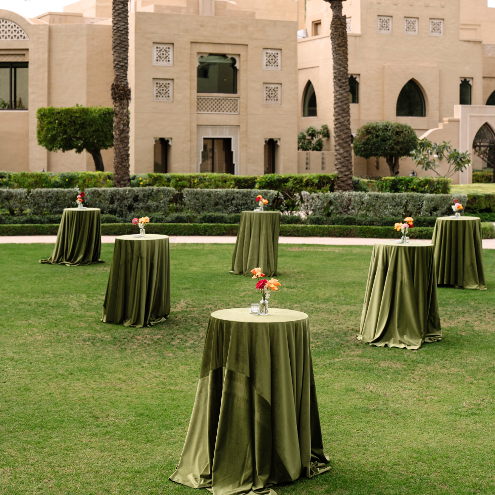 ROUND TABLECLOTH VELVET drapes elegantly over cocktail tables at an outdoor event setup, enhancing the ambiance with its sophisticated texture and style.