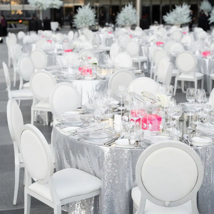 Elegant event setup featuring ROUND TABLECLOTH SEQUIN on round tables with glass chargers, floral centerpieces, and bright pink accents, ideal for formal occasions.